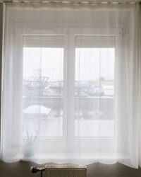 Rideau voilage anti-ondes blanc posé devant une fenêtre avec radiateur