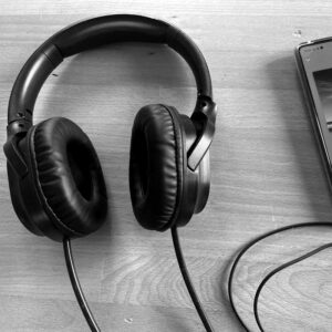 Casque filaire Air Tube noir avec tubes acoustiques, pos&eacute; &agrave; c&ocirc;t&eacute; d&rsquo;un smartphone